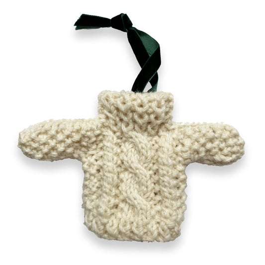 Mini Aran handknit Ireland Christmas ornament made from soft natural wool with traditional cable stitches, shown laid flat with a velvet ribbon attached.